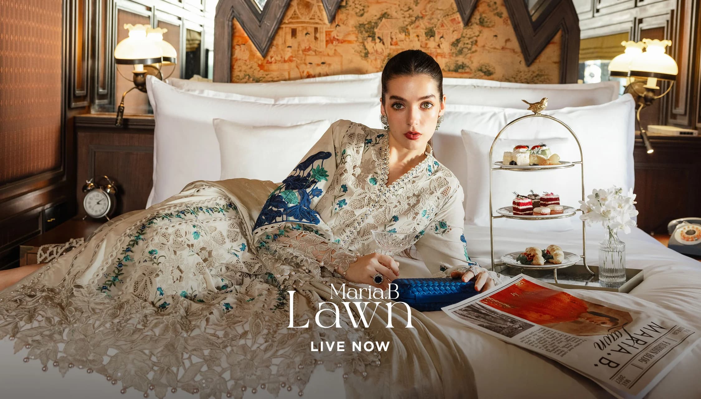 Lawn collection — model in embroidered lawn on a made bed with afternoon tea