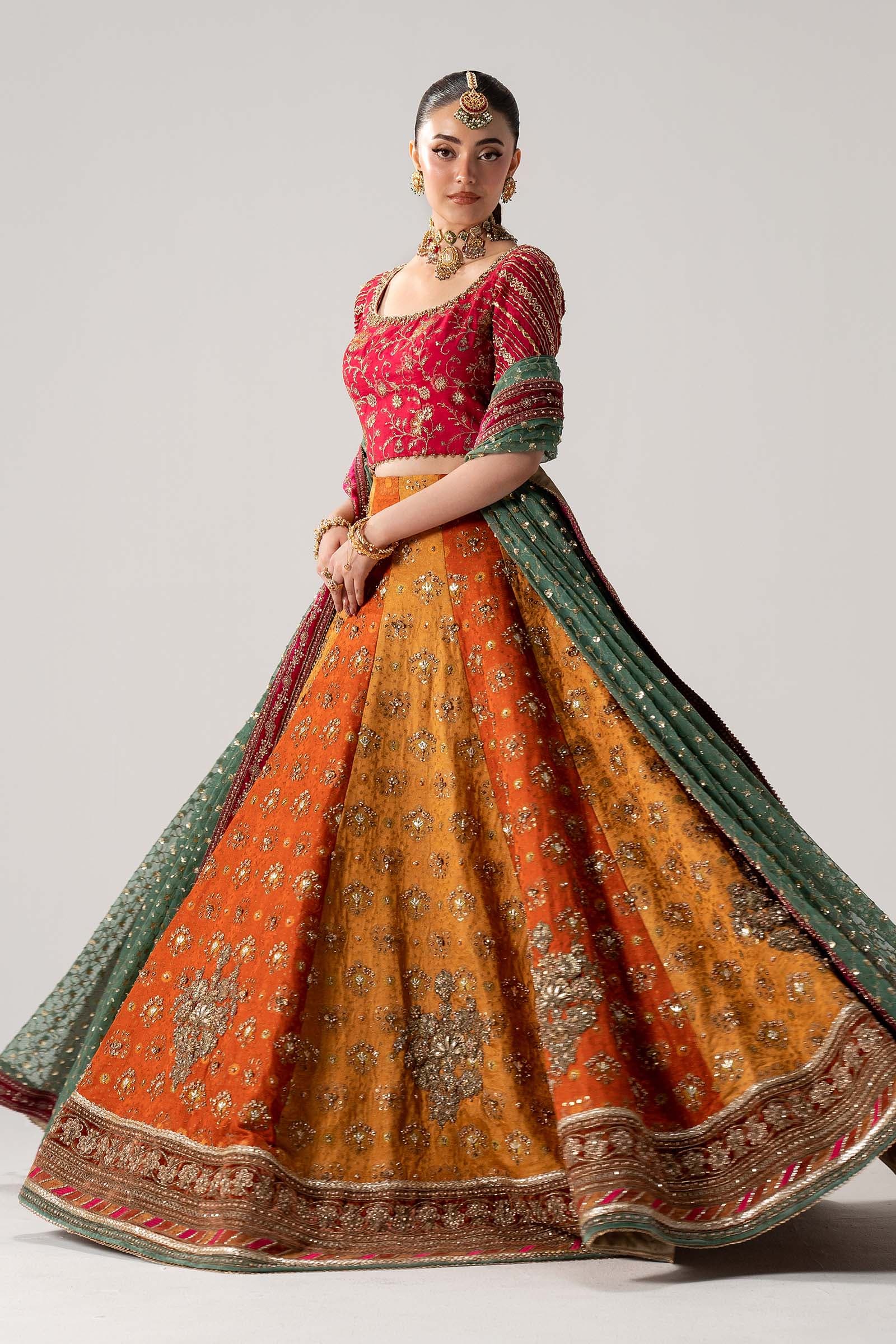 Model in a marigold couture lehenga with a green dupatta
