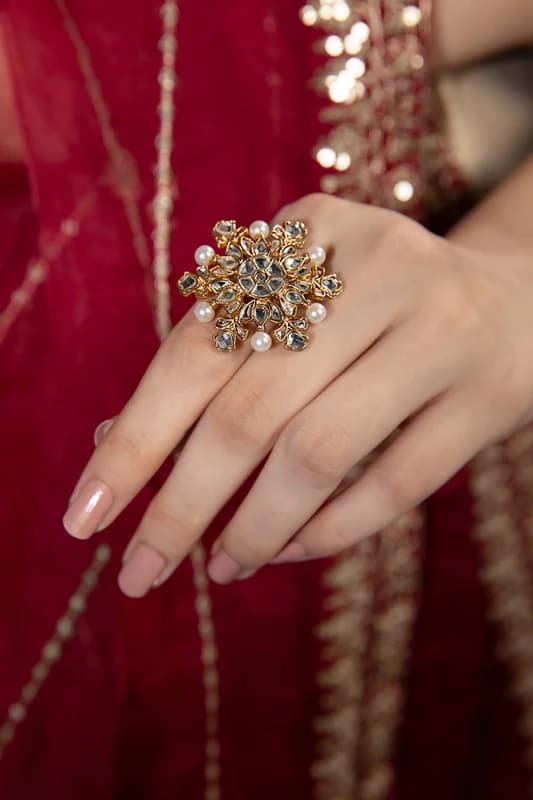 Floral kundan cocktail ring worn against a red kameez